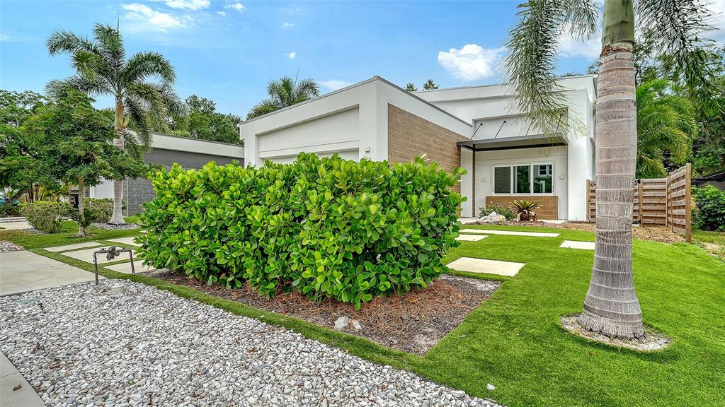 A modern white house with a large hedge, palm tree, and gravel landscaping in front — 2138 HAWTHORNE STREET, SARASOTA, FL