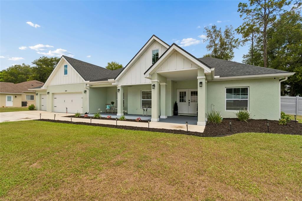 A light green single-story house with a white garage, covered porch, and dark roof — 36811 SUMMERS RIDGE DRIVE, DADE CITY, FL