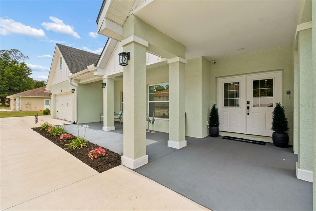 A light green house exterior features a covered front porch with white columns and doors — 36811 SUMMERS RIDGE DRIVE, DADE CITY, FL