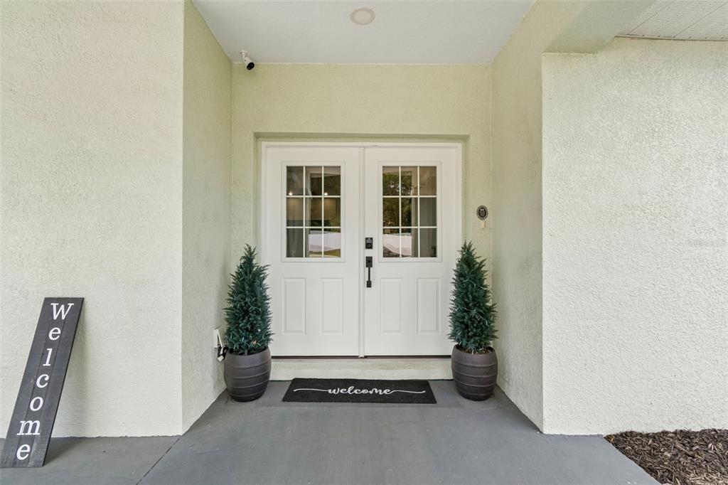 A front entryway features double white doors, two potted evergreen trees, and a welcome mat — 36811 SUMMERS RIDGE DRIVE, DADE CITY, FL