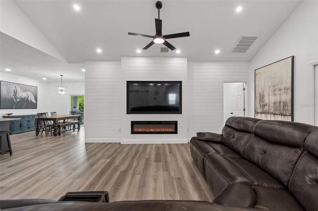 A living room features a white shiplap fireplace wall with a mounted television and electric fireplace — 36811 SUMMERS RIDGE DRIVE, DADE CITY, FL