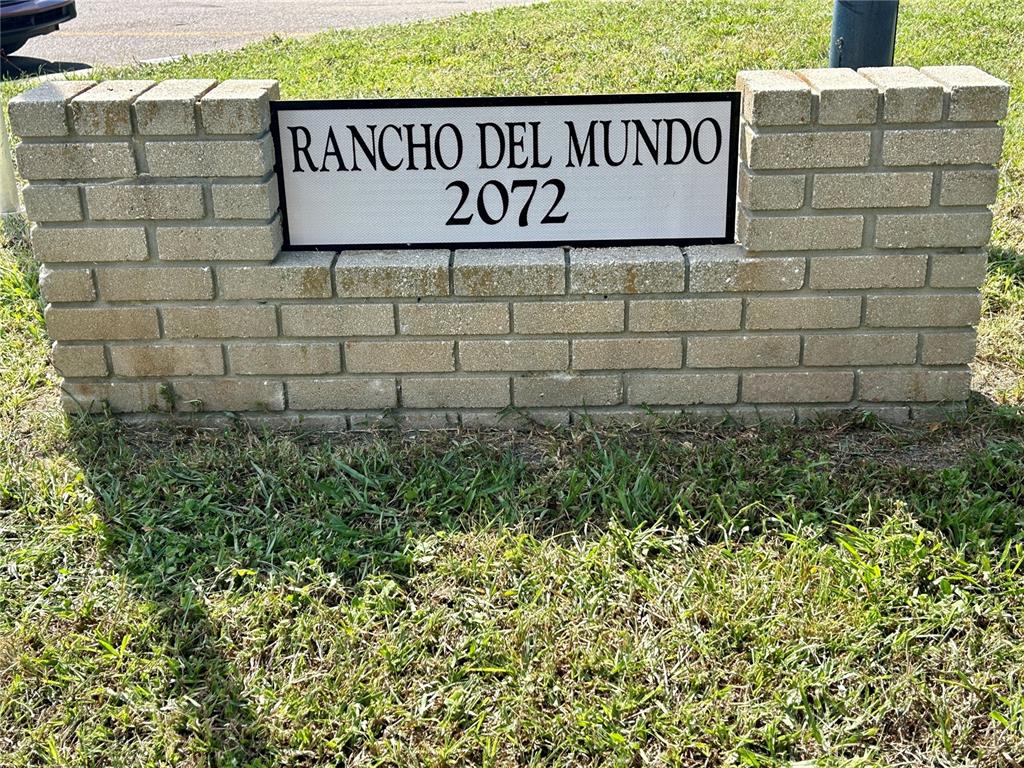 A brick wall features a sign reading Rancho Del Mundo 2072 set in the grass — 2073 DENMARK STREET UNIT 5, CLEARWATER, FL