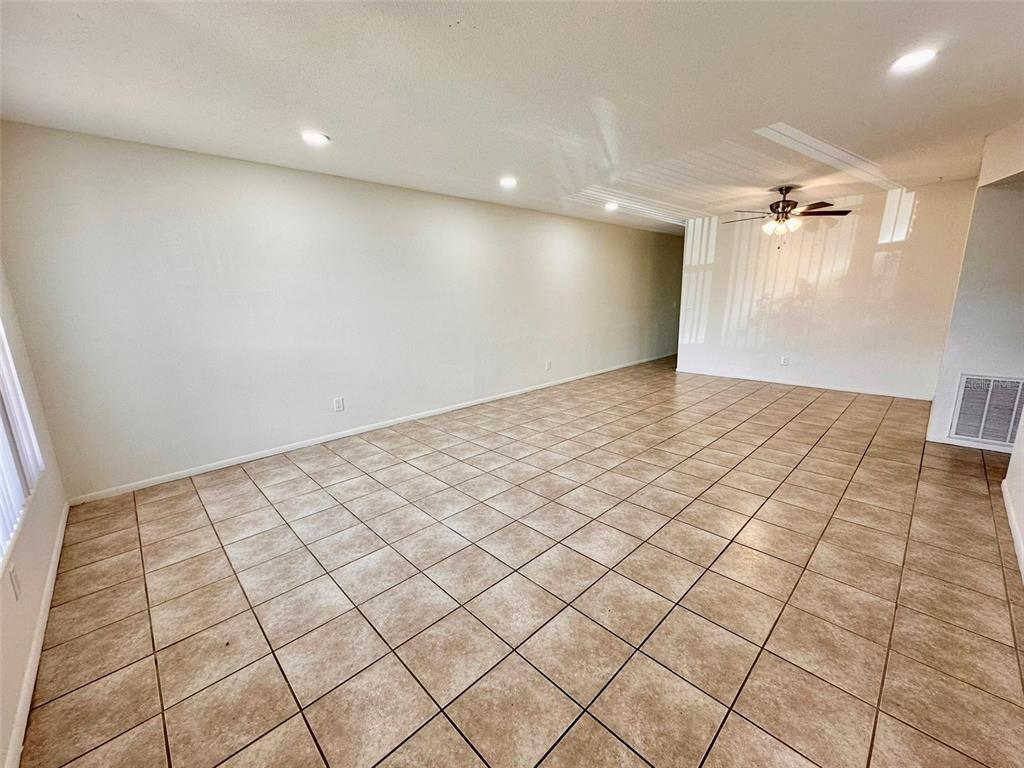 An empty room features beige tile flooring, recessed lighting, and a ceiling fan — 2073 DENMARK STREET UNIT 5, CLEARWATER, FL