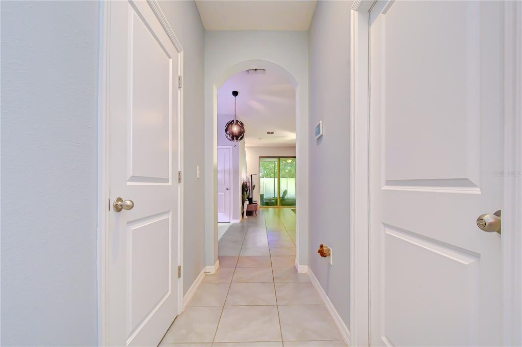 A tiled hallway leads through an arched doorway toward a living area with glass doors — 3143 PLEASANT WILLOW COURT, BRANDON, FL