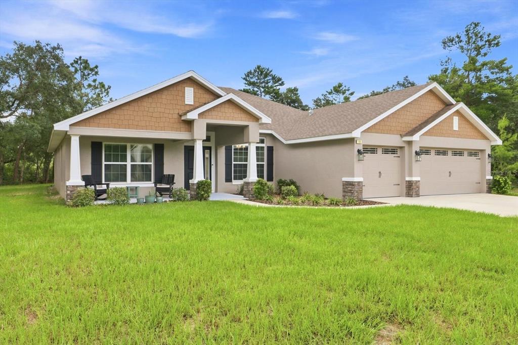 A single-story suburban house with a tan stucco exterior, brown shingle roof, and two-car garage — 14 LUPINE STREET, HOMOSASSA, FL