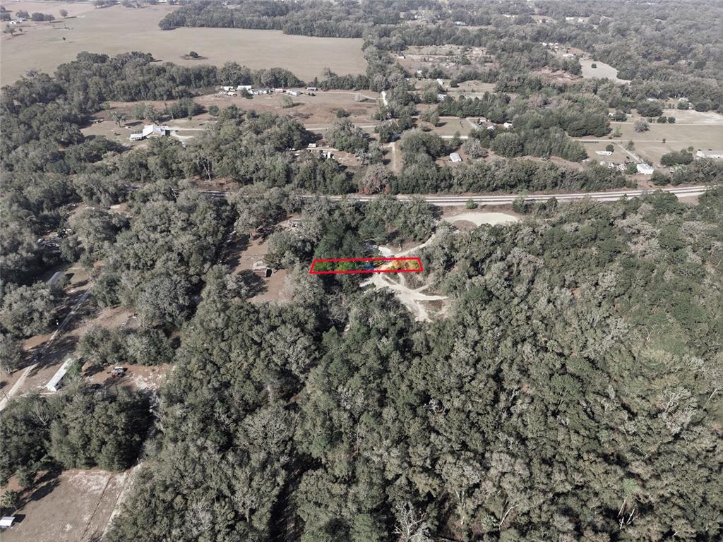 An aerial view shows a rectangular property outline highlighted in red amidst a wooded area — LOT 028 NE 164TH LANE, CITRA, FL