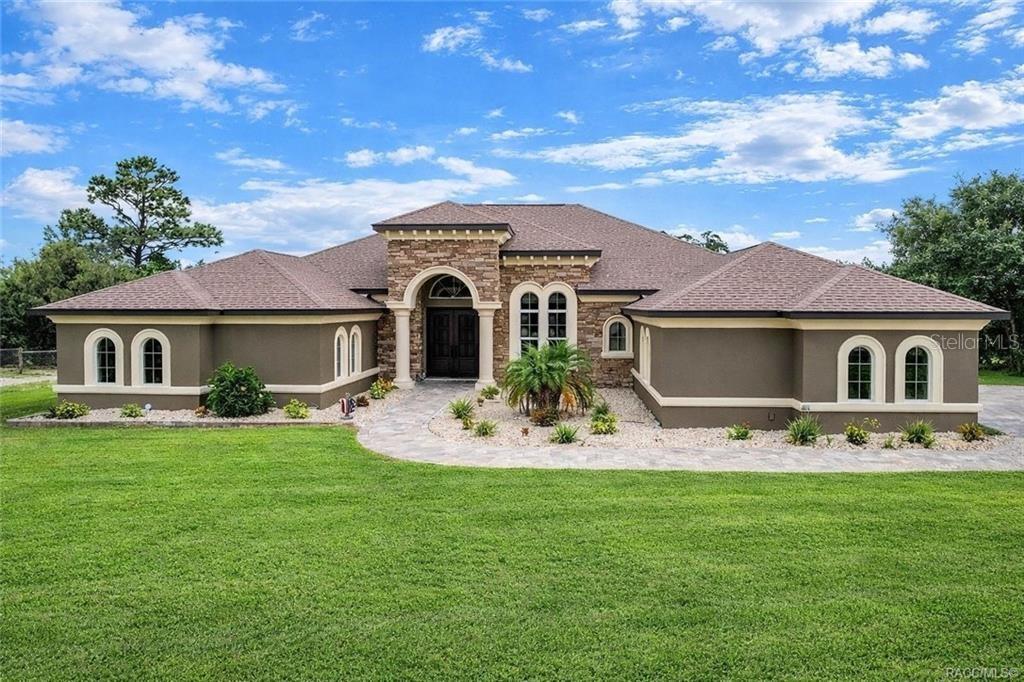 A single-story house with a stone-accented entryway, arched windows, and a stone walkway — 5061 W OAKHILL STREET, DUNNELLON, FL