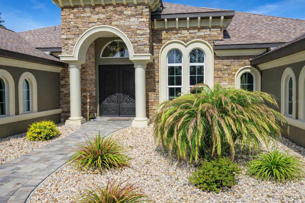 The exterior of a stone-faced house features an arched entryway with columns and double doors — 5061 W OAKHILL STREET, DUNNELLON, FL