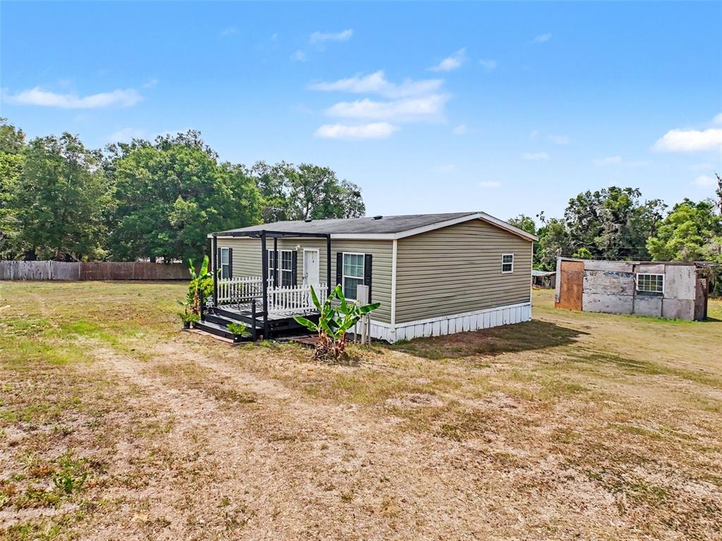 A single-story manufactured home with a small front porch sits on a large, grassy lot — 28402 SOARING HAWK LANE, BROOKSVILLE, FL