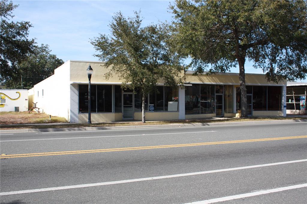 A single-story commercial building with large glass windows sits along a paved road — 710 N MAIN STREET, GAINESVILLE, FL