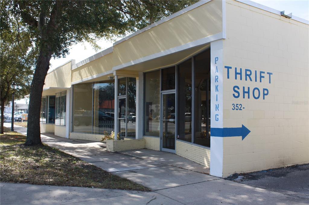 A single-story commercial building with a yellow facade, large glass windows, and thrift shop signage — 710 N MAIN STREET, GAINESVILLE, FL