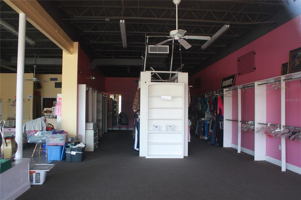 The interior of a retail store features pink walls, clothing racks, and a central shelving unit — 710 N MAIN STREET, GAINESVILLE, FL