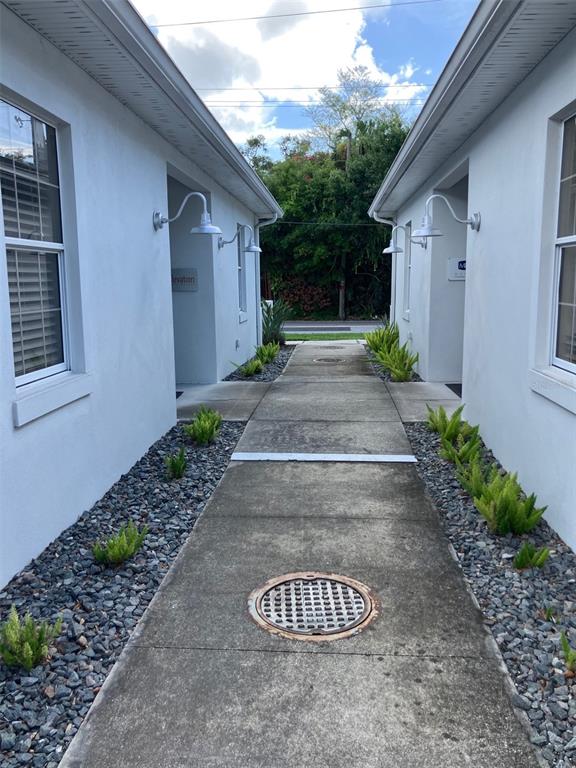 A concrete walkway leads between two white buildings with exterior wall-mounted lights and gravel landscaping — 5813 and 5815 S MACDILL AVENUE, TAMPA, FL