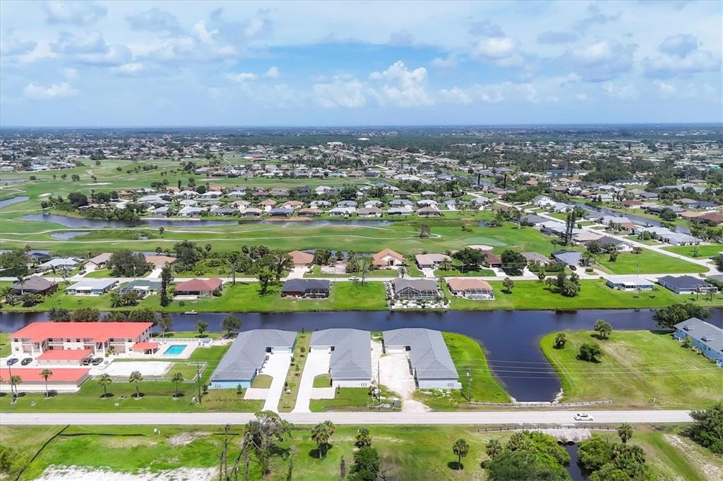 An aerial view shows a canal, residential homes, and a golf course under a blue sky — 236 BOUNDARY BOULEVARD, ROTONDA WEST, FL