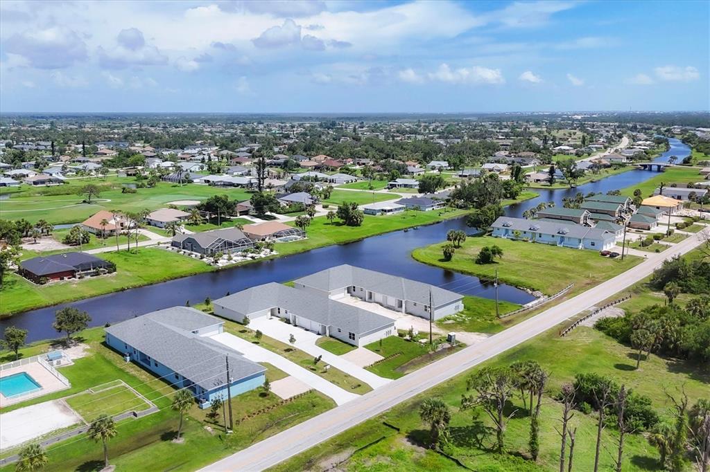 An aerial view shows a residential neighborhood with houses, a canal, and a paved road — 236 BOUNDARY BOULEVARD, ROTONDA WEST, FL