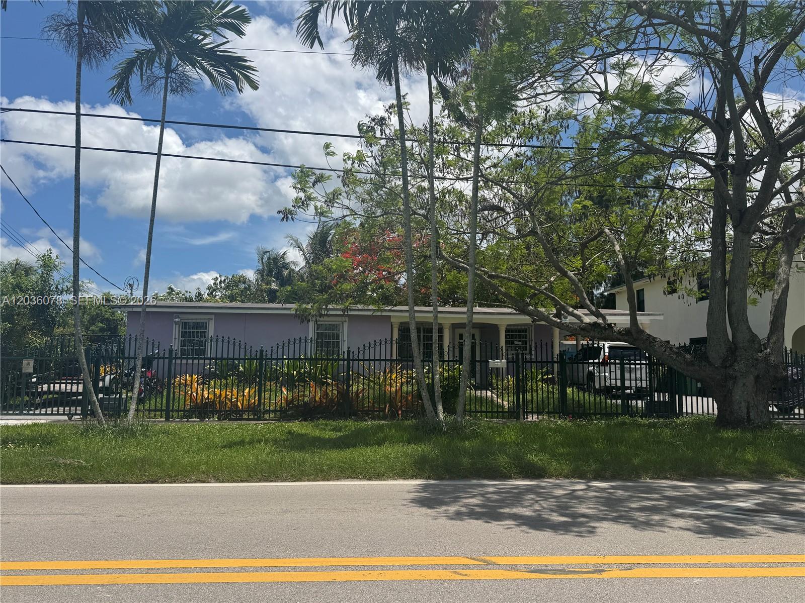 A single-story lavender house with a black metal fence stands behind a grassy lawn — 11290 SW 47th Ter, Miami FL 33165, MIAMI, FL