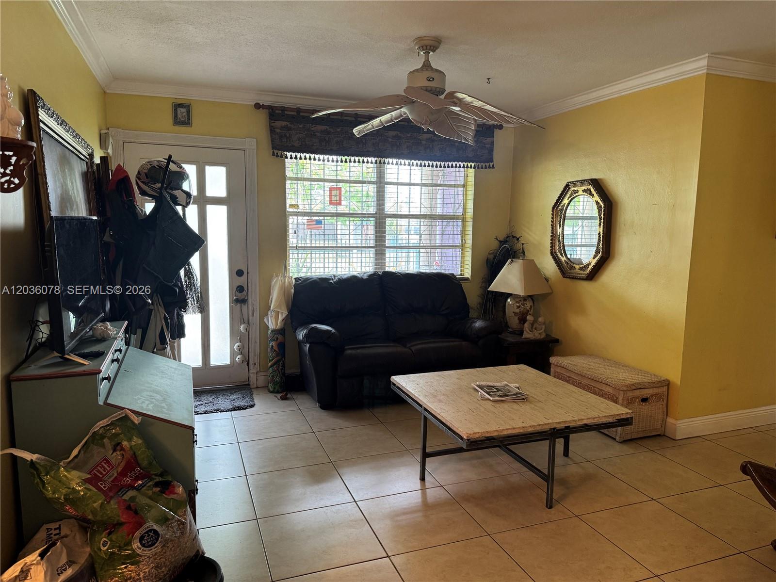 A living room features yellow walls, tile flooring, a black loveseat, and a ceiling fan — 11290 SW 47th Ter, Miami FL 33165, MIAMI, FL