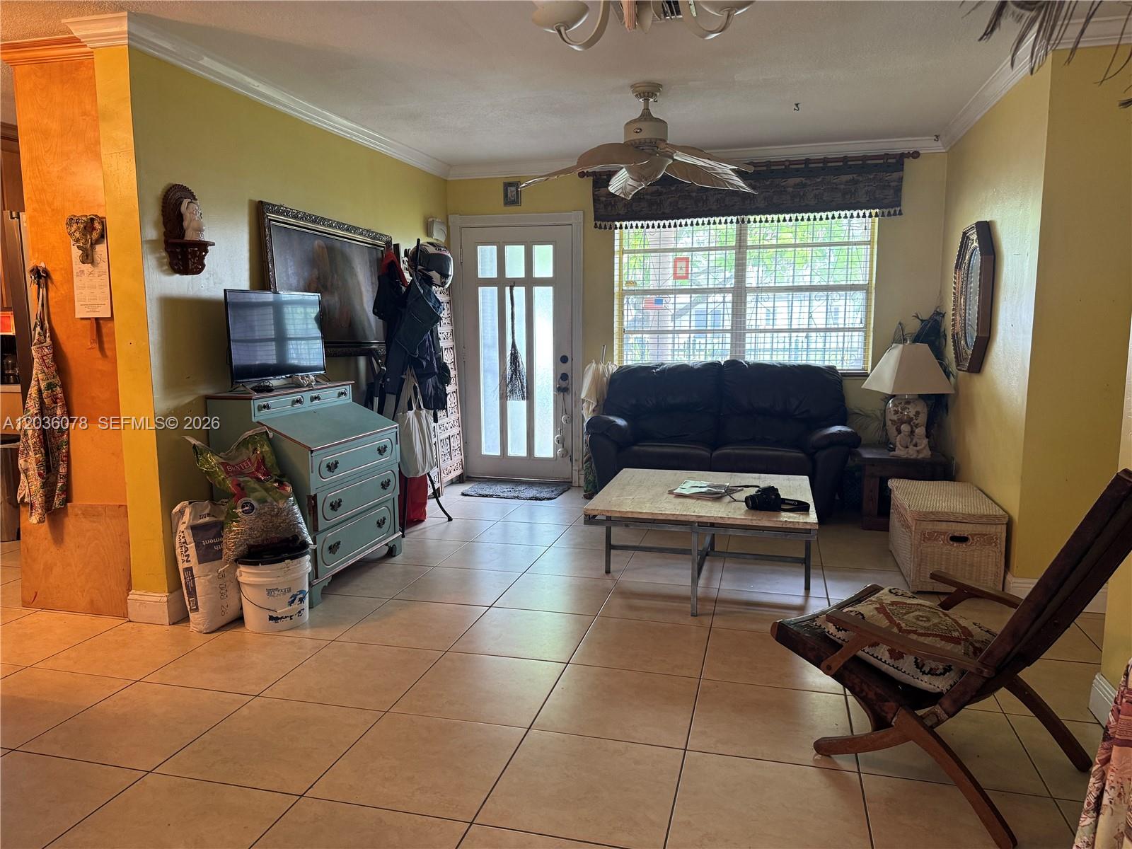 A living room features yellow walls, tile flooring, a ceiling fan, and a front door — 11290 SW 47th Ter, Miami FL 33165, MIAMI, FL