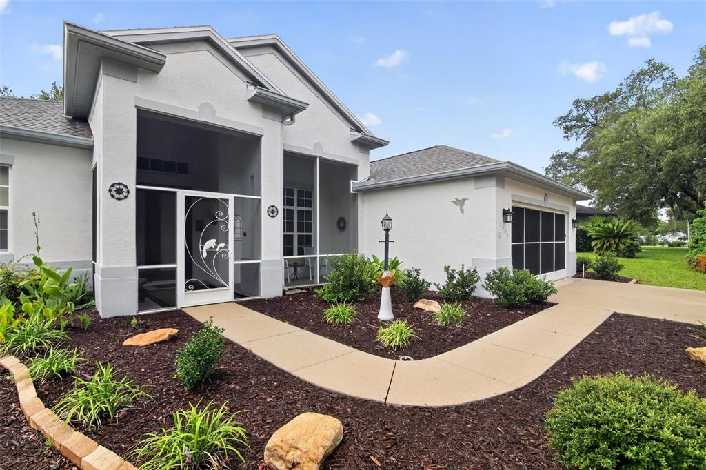 A single-story house with a screened entryway, a concrete walkway, and landscaped garden beds — 2457 N BRENTWOOD CIRCLE, LECANTO, FL