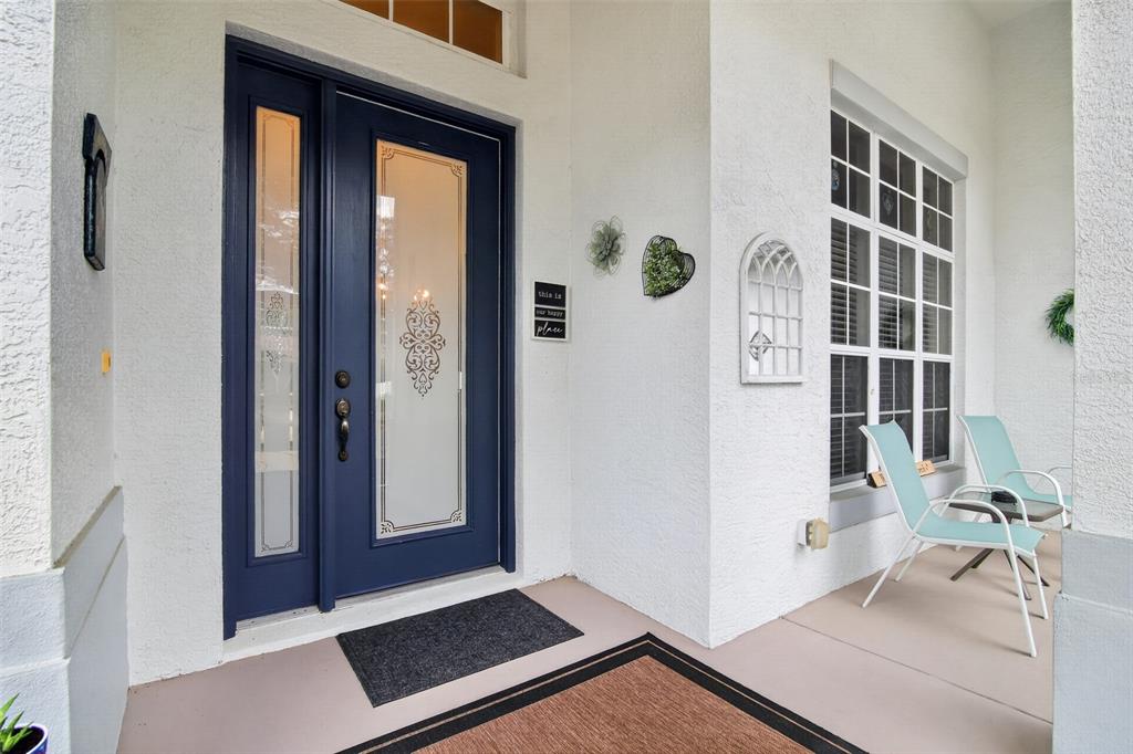 A blue front door with glass panels sits on a covered porch with two chairs — 2457 N BRENTWOOD CIRCLE, LECANTO, FL