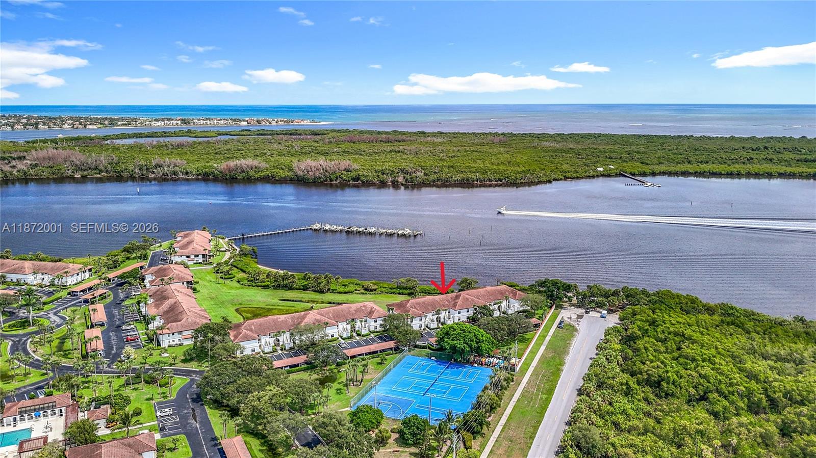 An aerial view shows a multi-unit residential building with a red arrow near a tennis court — 6082 SE Landing Way # 11, Stuart FL 34997, STUART, FL
