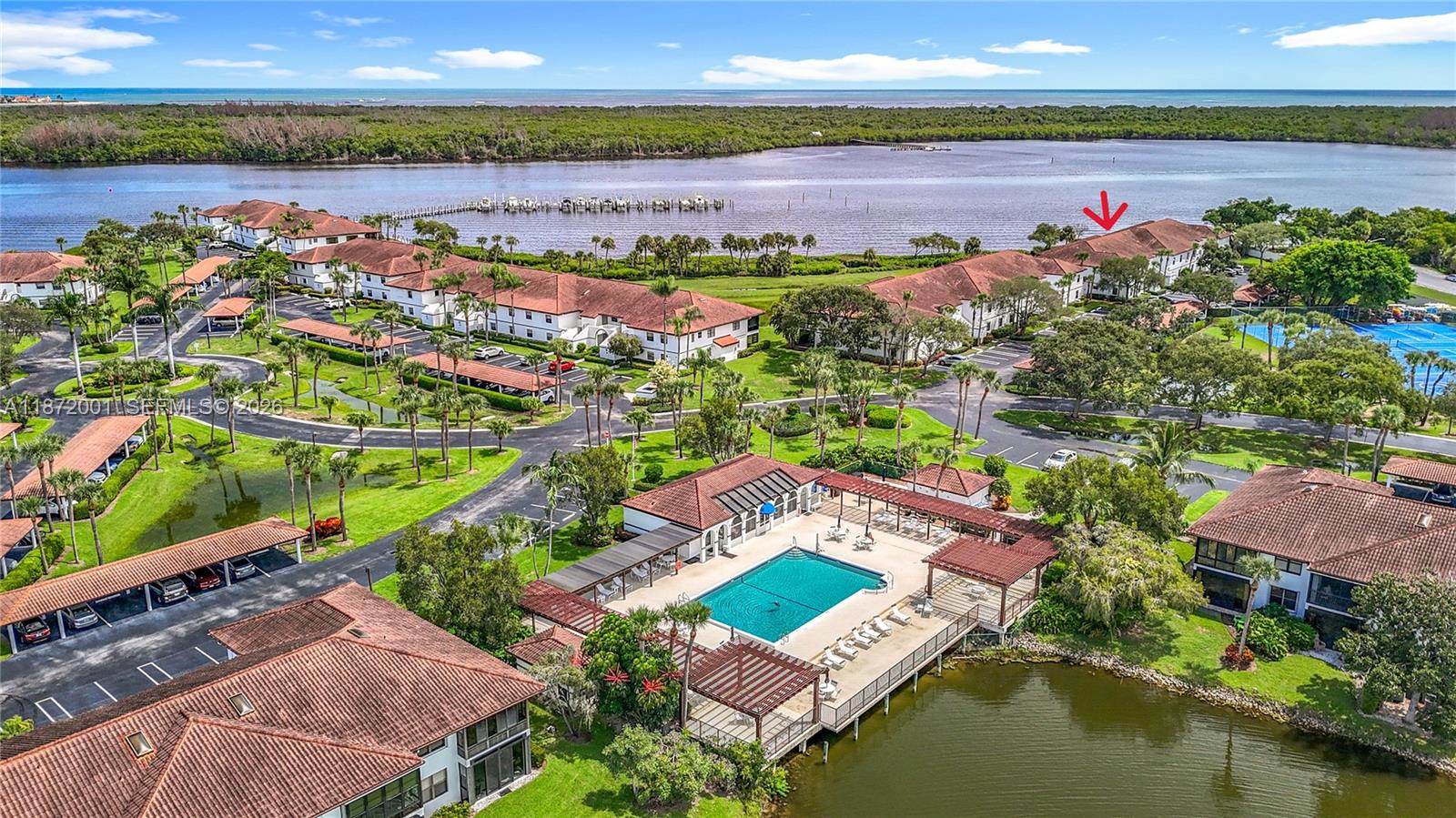 An aerial view shows a residential complex with a swimming pool, pond, and tennis courts — 6082 SE Landing Way # 11, Stuart FL 34997, STUART, FL
