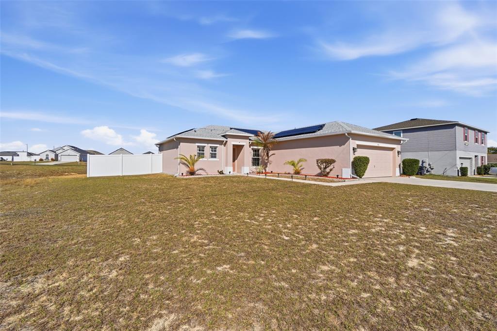 A single-story house with a tan exterior, solar panels, and a two-car garage — 995 CUMBERLAND DRIVE, KISSIMMEE, FL