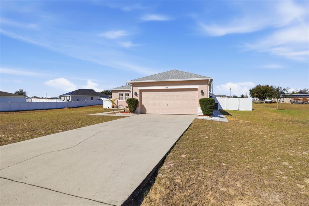 A single-story house with a beige exterior, a two-car garage, and a concrete driveway — 995 CUMBERLAND DRIVE, KISSIMMEE, FL