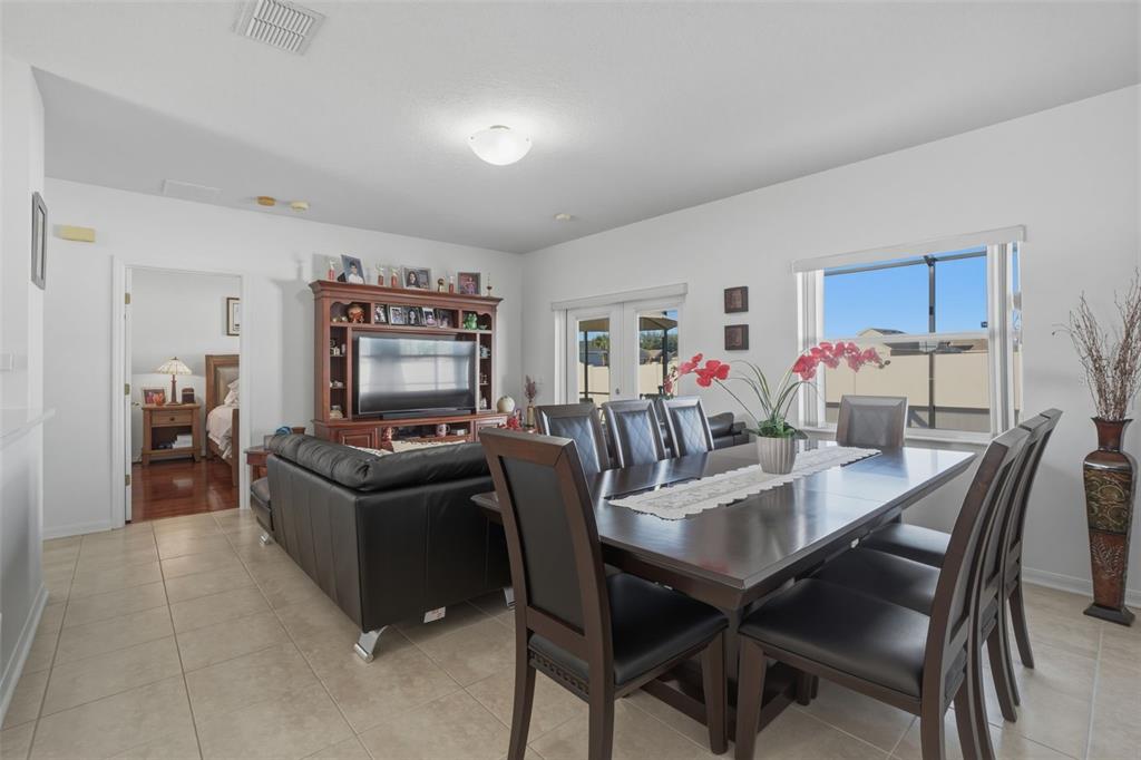A dining area with a dark wood table and chairs sits beside a living room — 995 CUMBERLAND DRIVE, KISSIMMEE, FL