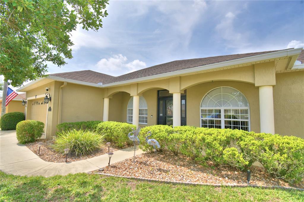 A single-story house with a tan stucco exterior, arched porch columns, and a landscaped yard — 112 WATERVIEW CIRCLE, AUBURNDALE, FL