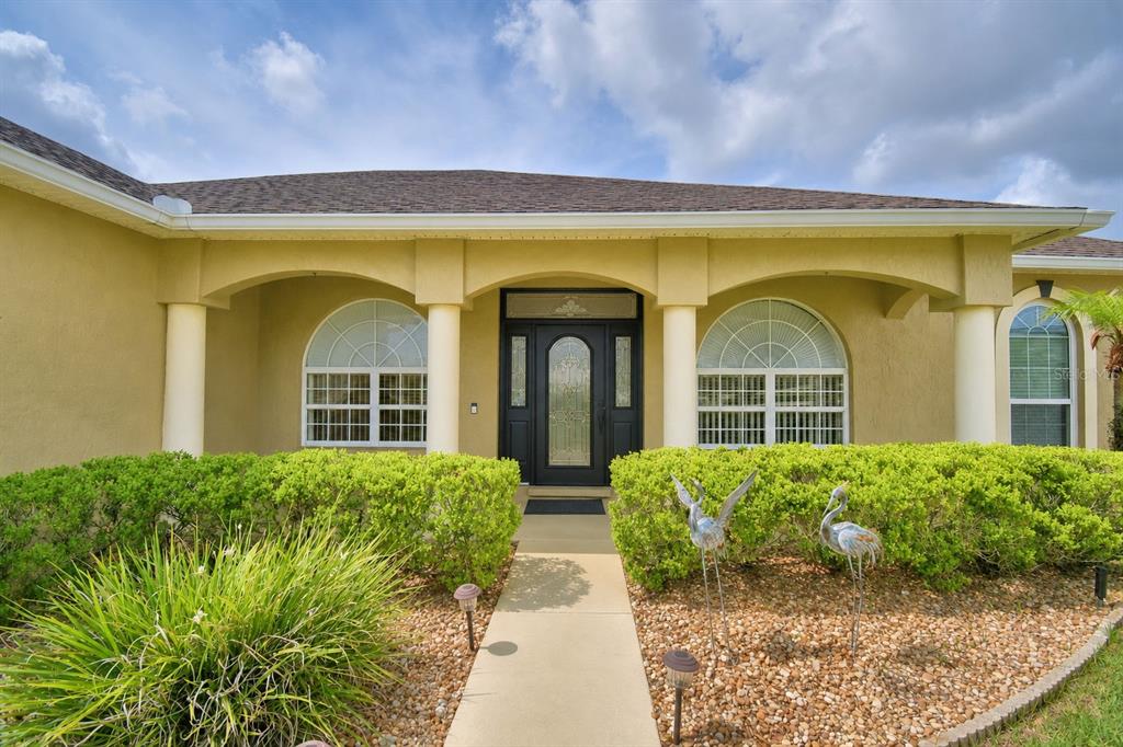 The front exterior of a house features a covered entryway with columns and arched windows — 112 WATERVIEW CIRCLE, AUBURNDALE, FL