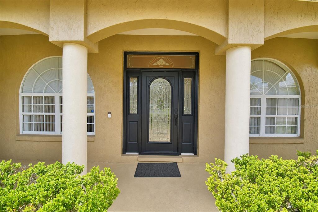 A front entryway with a dark glass-paneled door, two side windows, and two white columns — 112 WATERVIEW CIRCLE, AUBURNDALE, FL