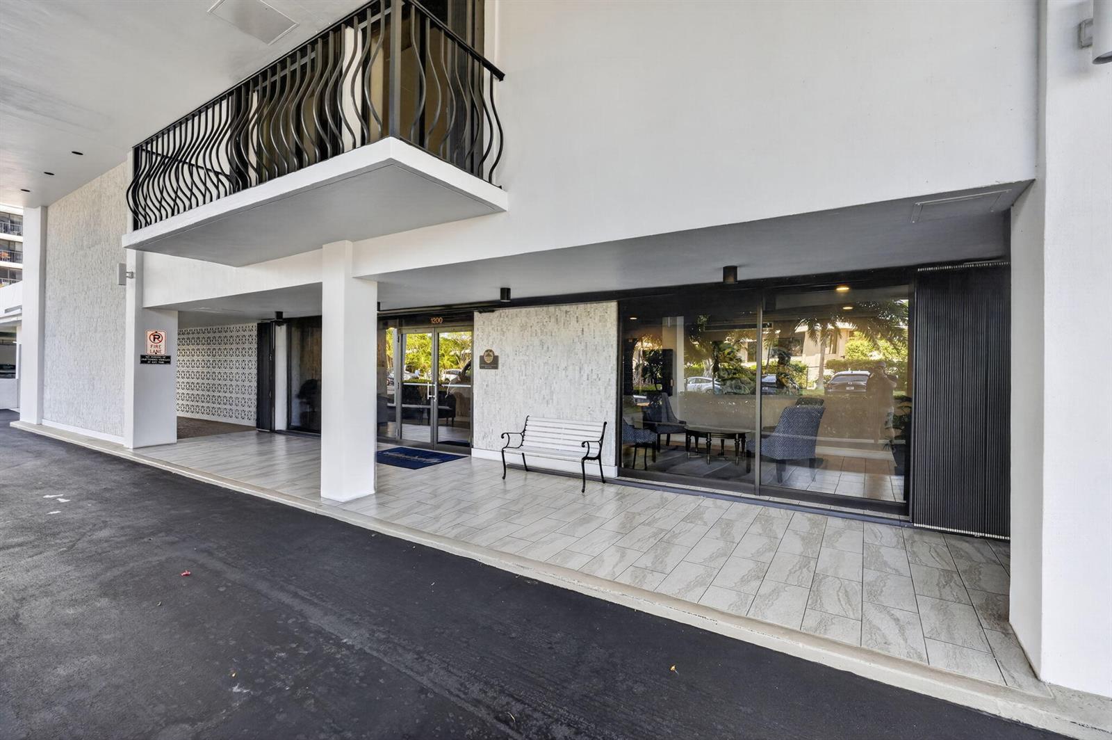 The exterior entrance of a building features a covered walkway, glass doors, and a bench — 1200 Marine Way, North Palm Beach FL 33408, NORTH PALM BEACH, FL