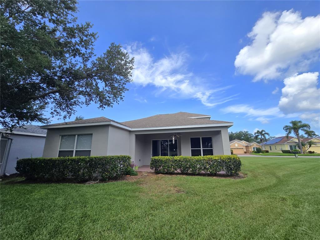 The rear exterior of a single-story house features a covered patio and a manicured lawn — 3637 SUMMERWIND CIRCLE, BRADENTON, FL
