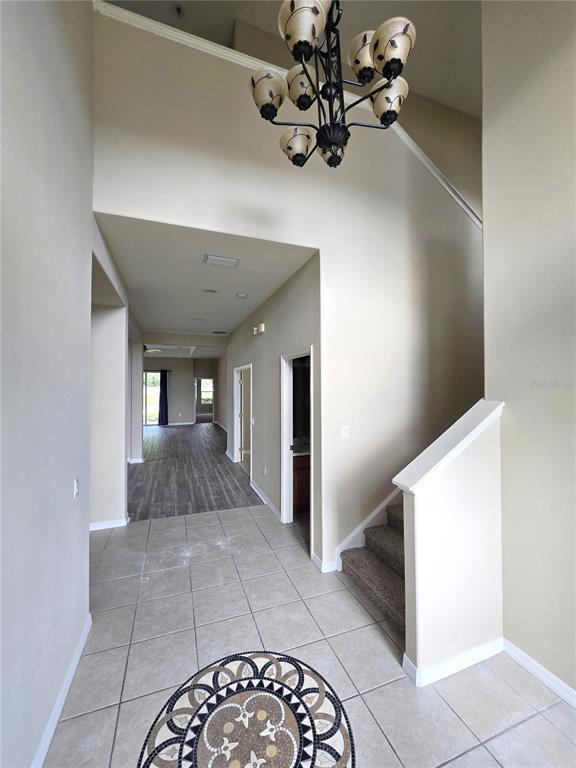 A tiled entryway features a chandelier, a staircase with carpeted steps, and a view into a hallway — 3637 SUMMERWIND CIRCLE, BRADENTON, FL
