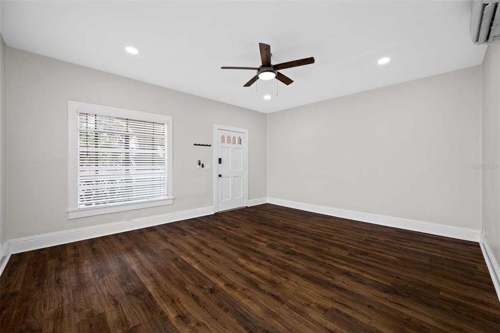 An empty room with dark wood-look flooring, light gray walls, a ceiling fan, and a door — 1700 PARK STREET N UNIT 105, ST PETERSBURG, FL