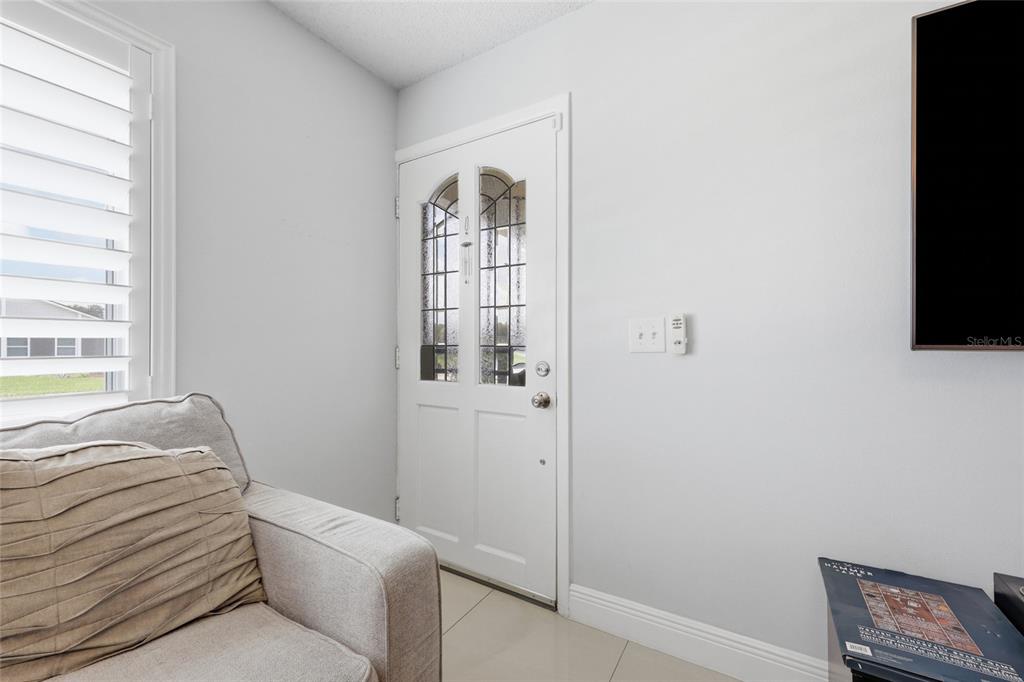 A living room features a white front door with glass panels and a beige sofa — 931 ARIZONA WOODS LANE, ORLANDO, FL