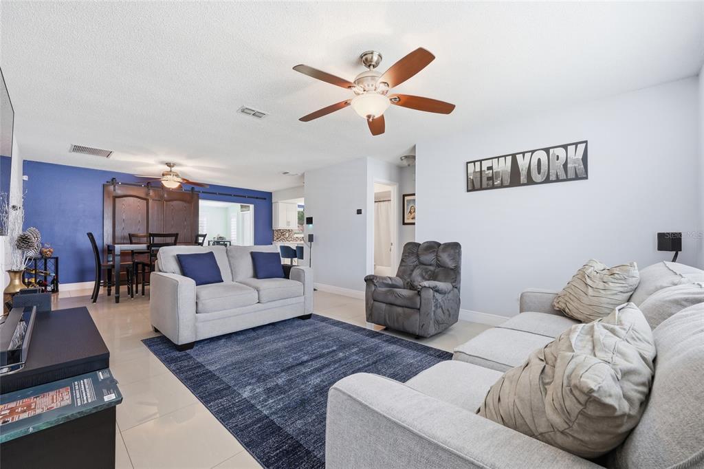 A living room features light gray sofas, a dark blue area rug, and a ceiling fan — 931 ARIZONA WOODS LANE, ORLANDO, FL