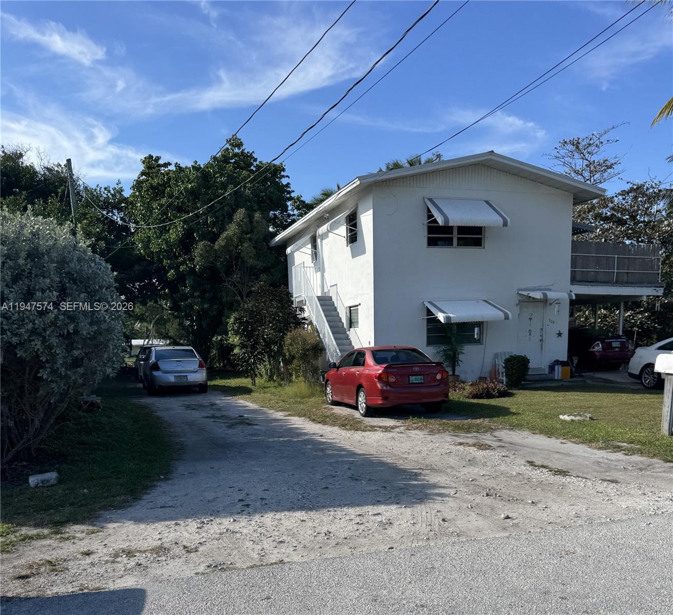 A two-story white house with a second-floor balcony sits on a grassy lawn — 329 63rd Court Gulf, Marathon FL 33050, MARATHON, FL