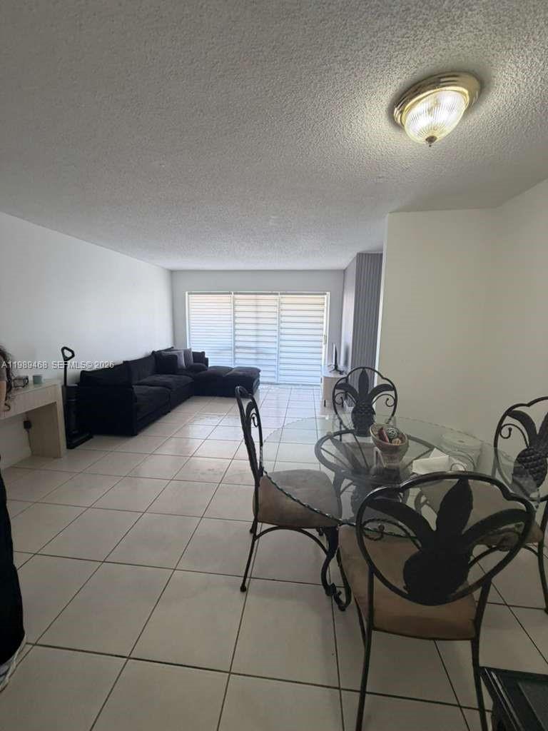 A living and dining area features white tile floors, a black sectional sofa, and glass-topped table — 4154 NW 79th Ave # 2A, Doral FL 33166, DORAL, FL