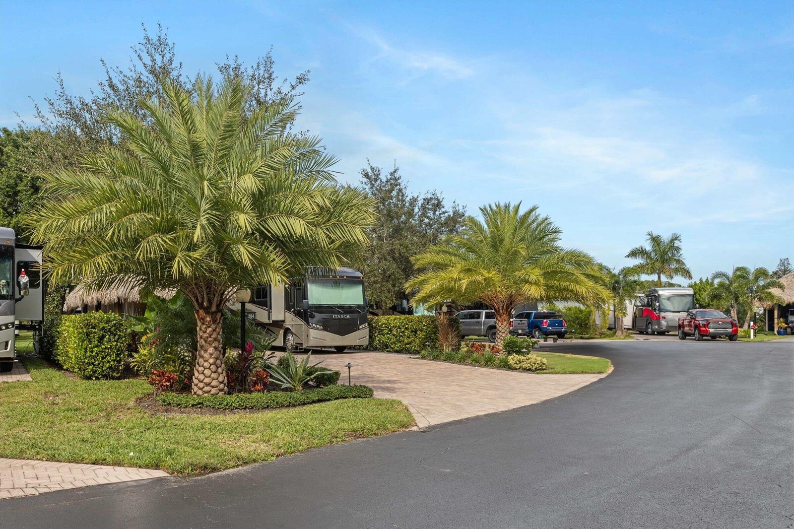 A paved driveway leads to an RV parked under palm trees in a sunny landscape — 204 N Cortez Drive # 204, Margate FL 33068, MARGATE, FL