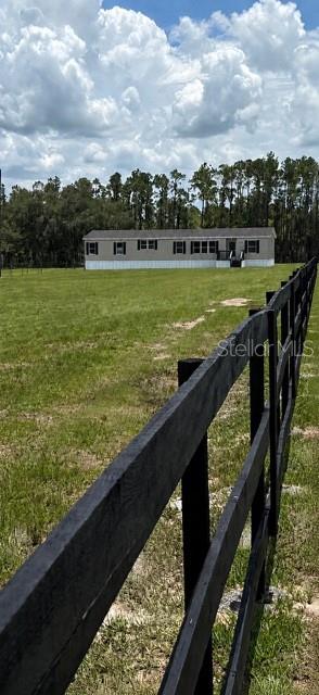 A single-story manufactured home sits in a grassy field behind a black wooden fence — 3483 BROOKE SMITH ROAD, FORT MEADE, FL