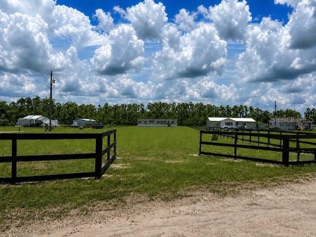 A grassy field with a black fence in the foreground and mobile homes in the distance — 3483 BROOKE SMITH ROAD, FORT MEADE, FL