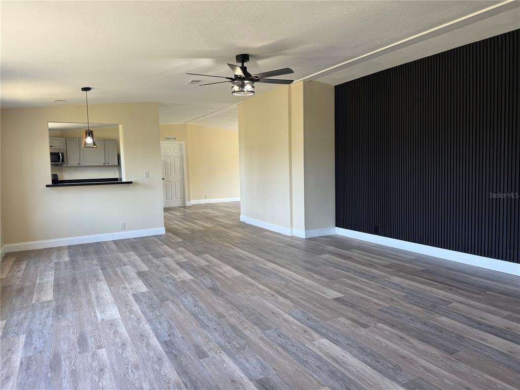 A living room features wood-look flooring, a black slat accent wall, and a ceiling fan — 3483 BROOKE SMITH ROAD, FORT MEADE, FL