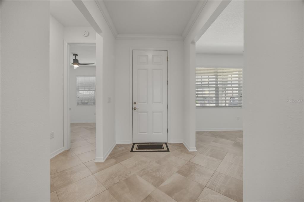 A tiled entryway features a white front door and openings to adjacent rooms — 9070 SW 106TH AVENUE, OCALA, FL