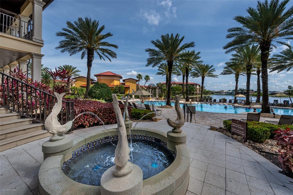 A stone fountain with fish sculptures sits on a patio overlooking a resort-style swimming pool — 99 VIVANTE BOULEVARD UNIT 404, PUNTA GORDA, FL
