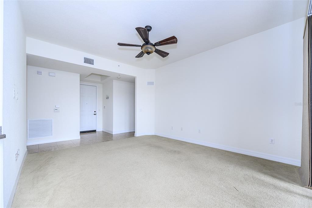 An empty room with beige carpet, white walls, a ceiling fan, and a white door — 99 VIVANTE BOULEVARD UNIT 404, PUNTA GORDA, FL