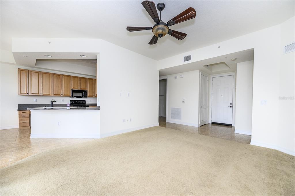 A living room with beige carpet opens to a kitchen with light wood cabinets — 99 VIVANTE BOULEVARD UNIT 404, PUNTA GORDA, FL