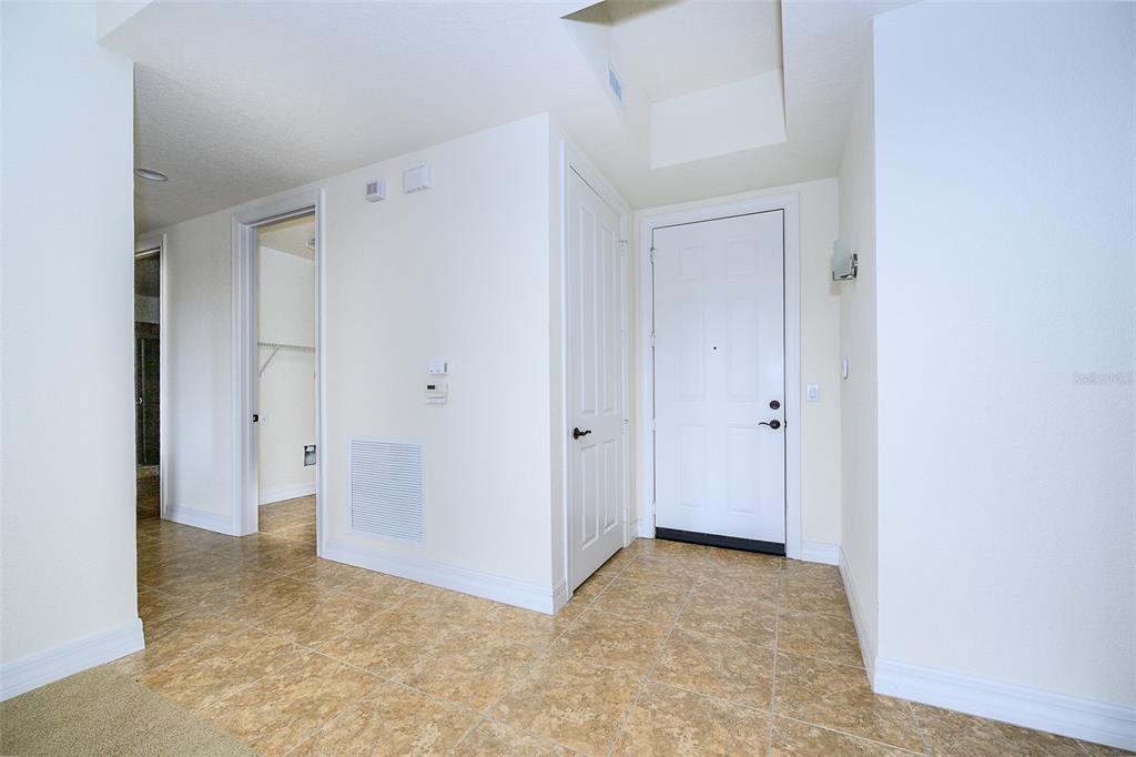 An interior entryway with tile flooring, a white front door, and a closet door — 99 VIVANTE BOULEVARD UNIT 404, PUNTA GORDA, FL