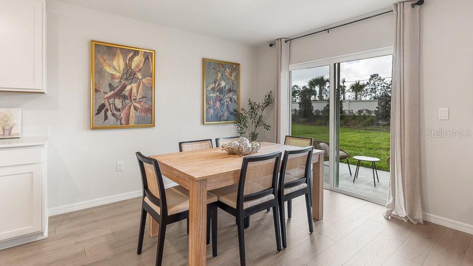 A dining room features a wooden table, black chairs, wall art, and a sliding glass door — 10904 44TH AVENUE E, PALMETTO, FL